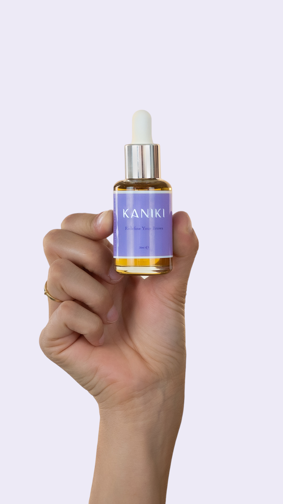 Foto van een hand die het Kaniki Elixir voor wenkbrauwen flesje vasthoudt, waarbij het etiket en de flesinhoud duidelijk zichtbaar zijn, benadrukkend de specifieke wenkbrauwverzorgingseigenschappen van dit product.
